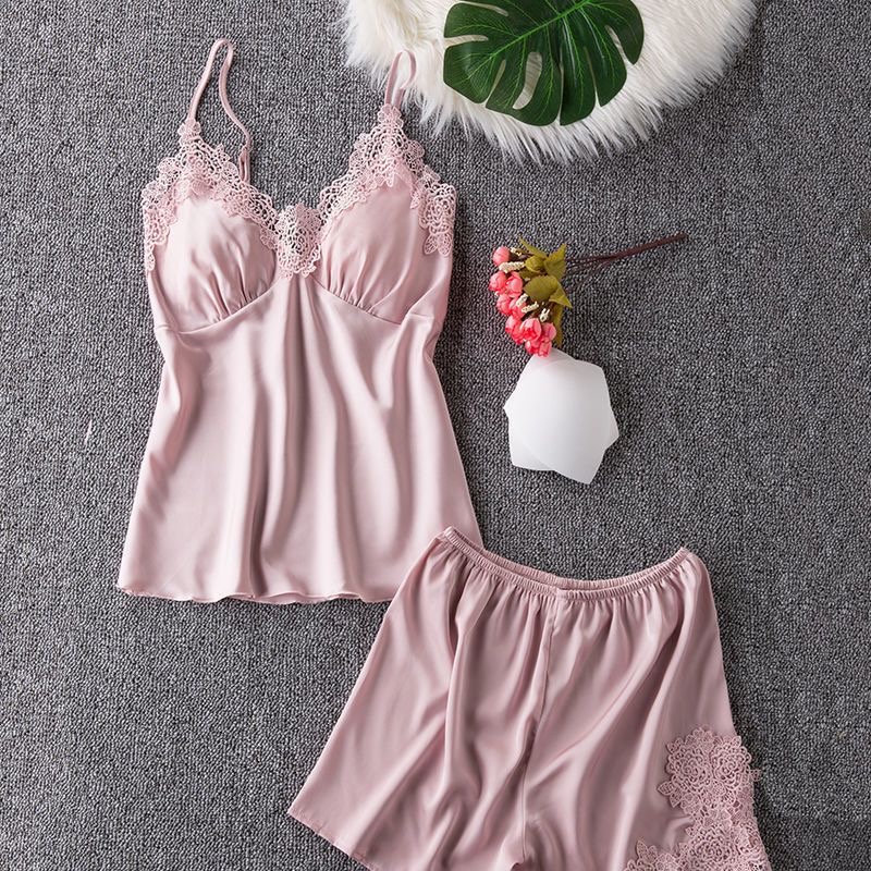 Women’s dusty‑pink satin camisole‑shorts pajama set, thin spaghetti straps, V‑neck trimmed with delicate floral lace, built‑in padded cups, elastic‑waist shorts with matching lace appliqués on side hem, soft glossy satin material, gentle feminine home sleepwear.