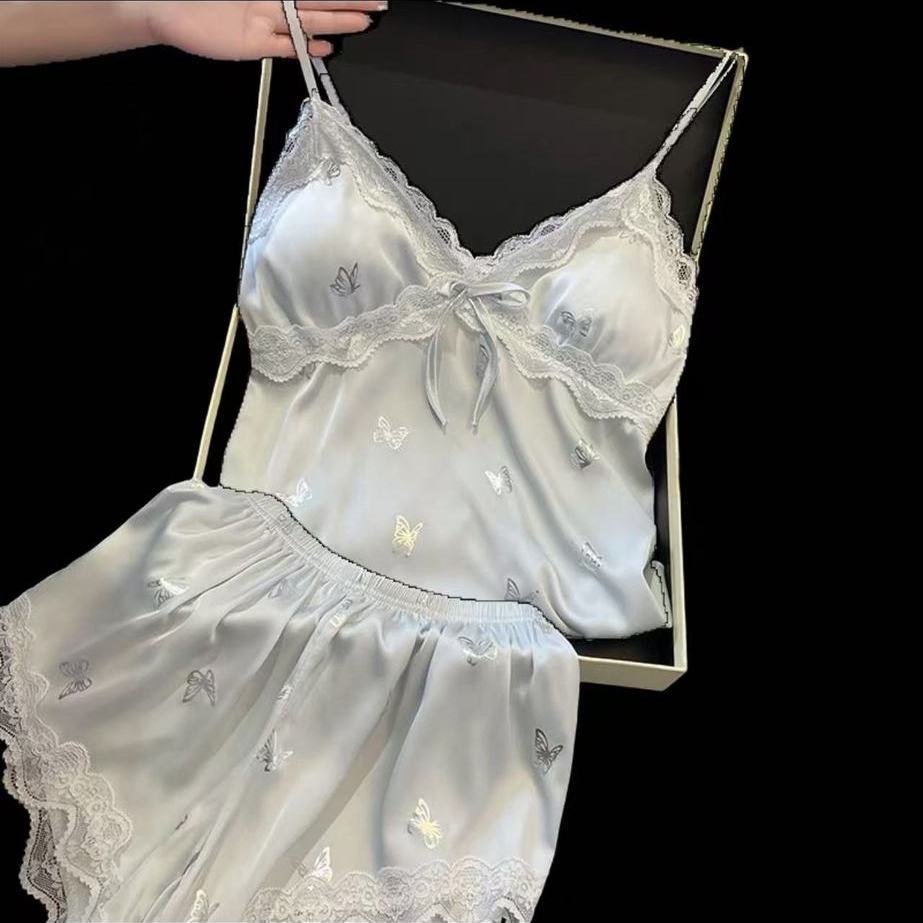 Women’s light‑blue satin camisole‑shorts sleepwear set, all‑over butterfly print, V‑neck trimmed with delicate lace and front bow detail, built‑in chest pads, elastic‑waist shorts with lace scalloped hem, silky glossy fabric, sweet feminine loungewear.