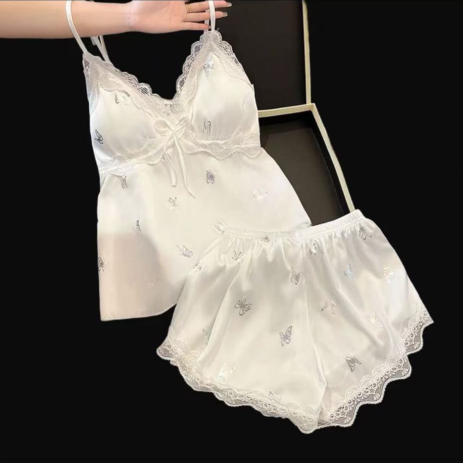 Women’s white satin camisole‑shorts pajama set, iridescent butterfly all‑over print, V‑neck with scalloped lace trim and front bow detail, built‑in padded cups, elastic‑waist shorts finished with lace scalloped hem, shiny silky texture, delicate romantic loungewear.